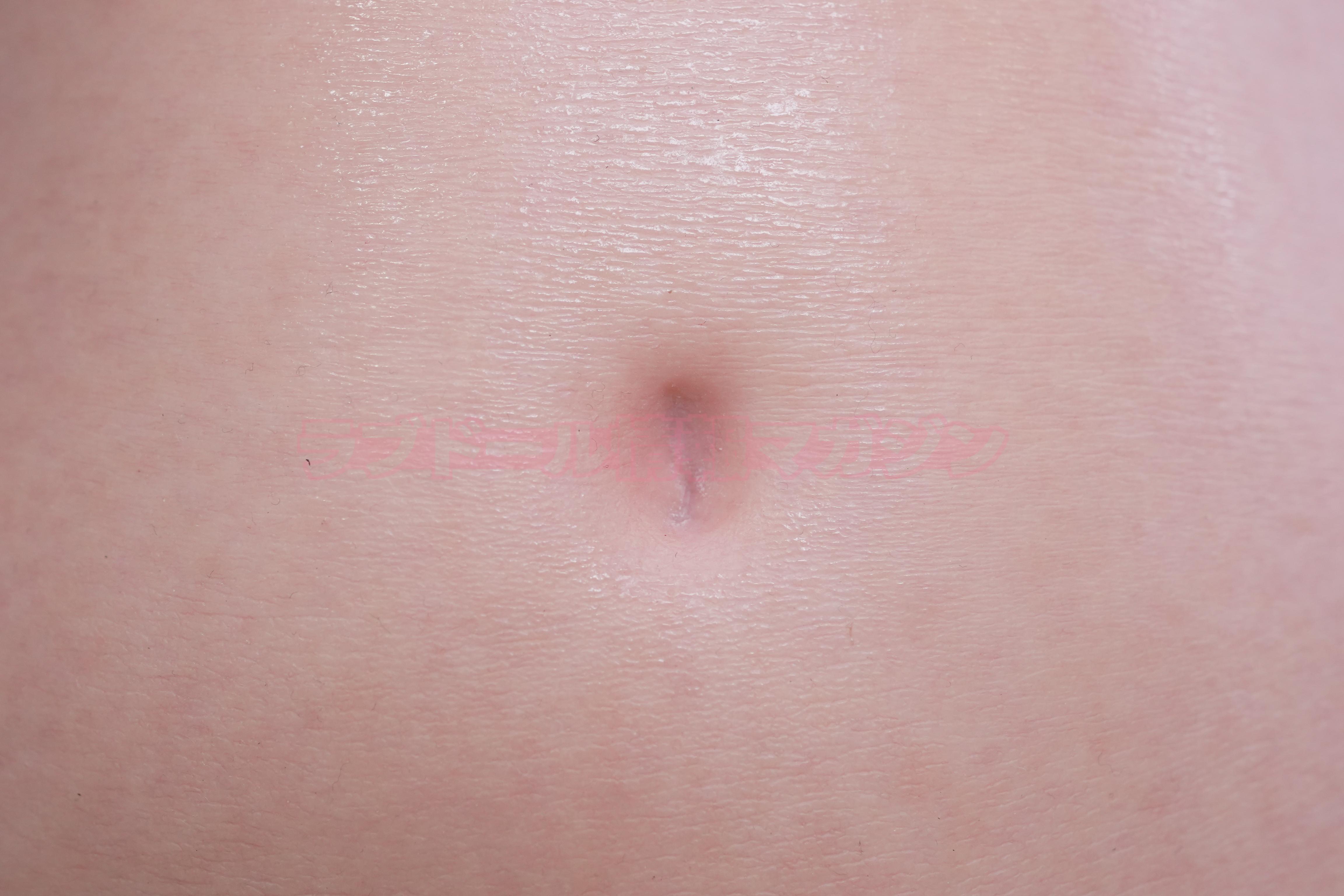 Close-up image of a smooth and realistic-looking human skin texture with a navel, showcasing detailed skin features.