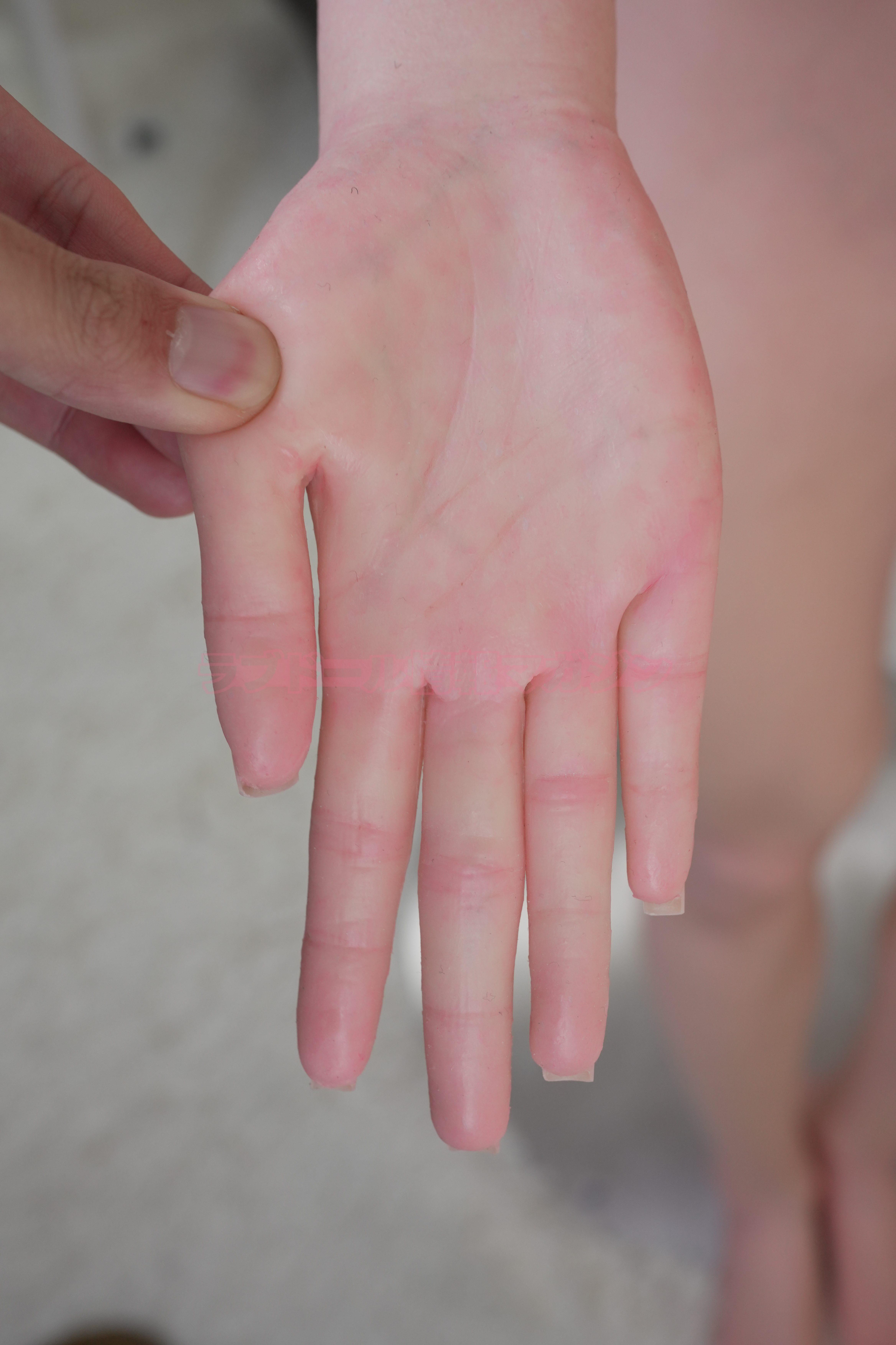 Close-up of a lifelike silicone doll hand being squeezed, showcasing the realistic texture and details.