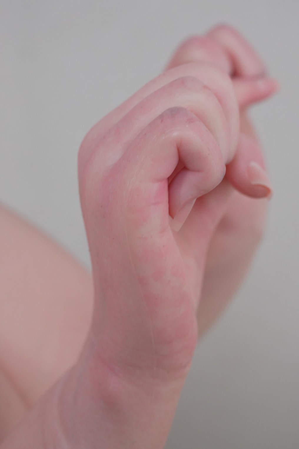 Close-up image of a realistic silicone doll's hand showing skin details and finger positioning.