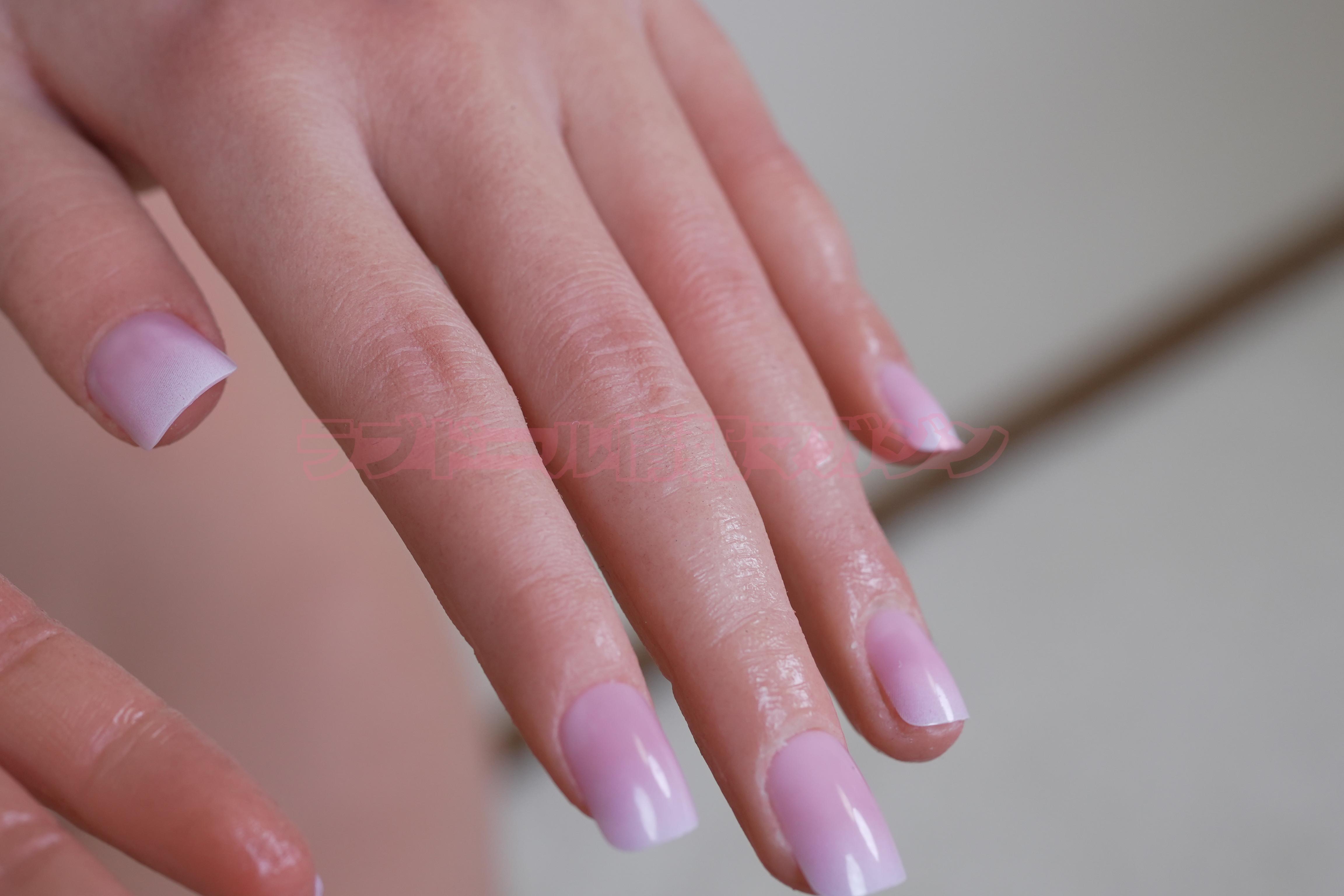 Close-up of a realistic hand with pink gradient nails on a light background.