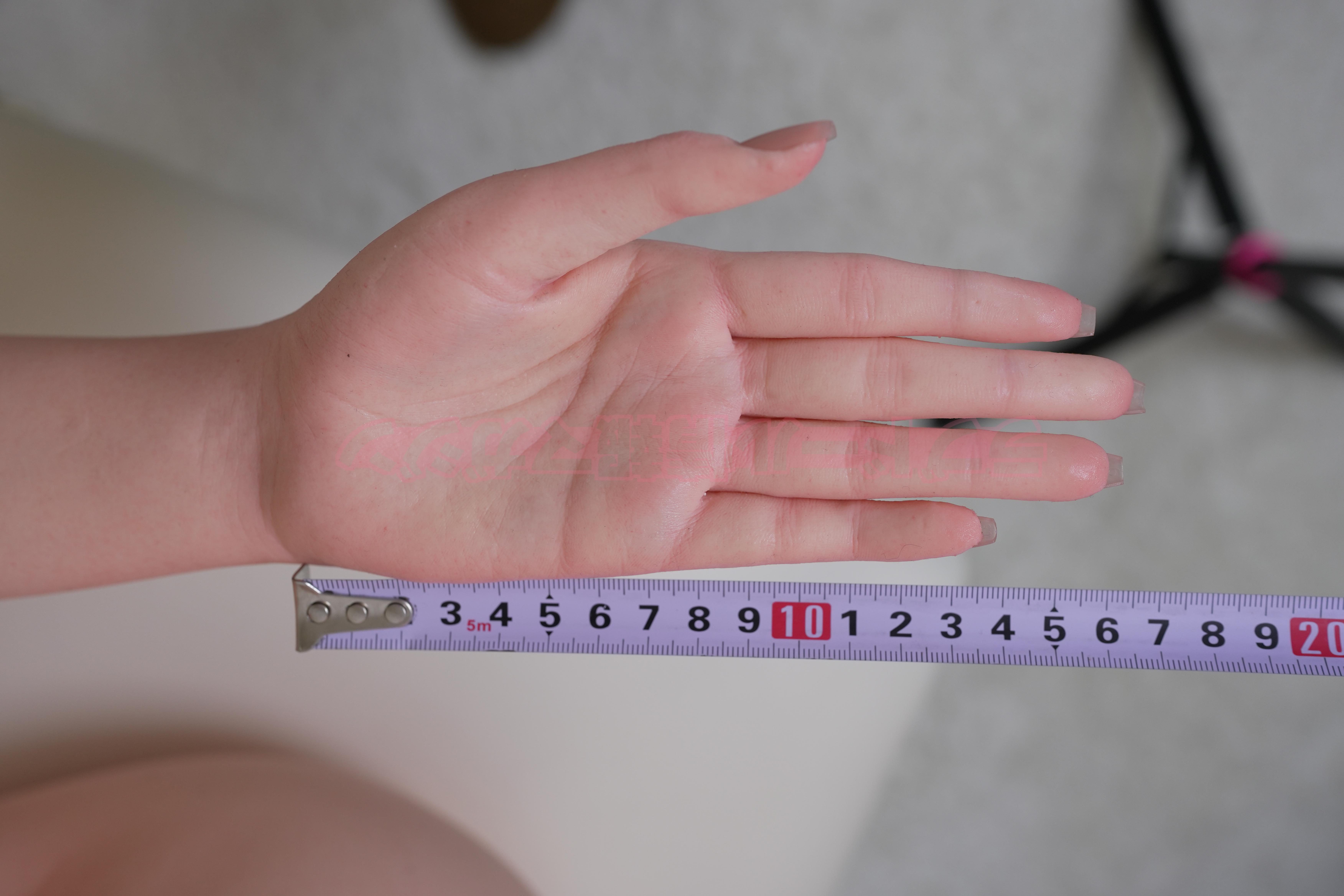 A close-up photo of a hand measuring approximately 10 cm wide with a ruler, resting on a flat surface.