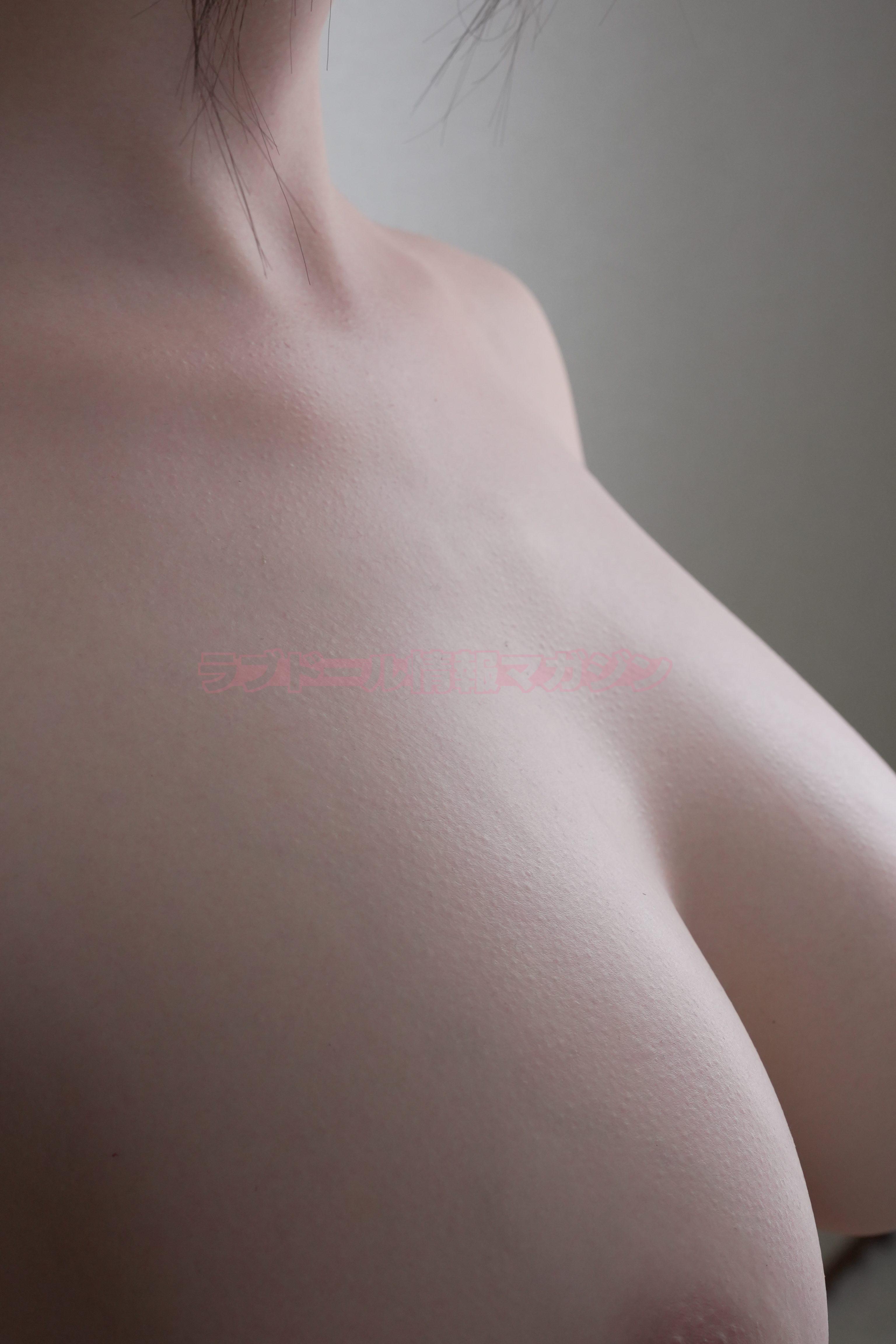 Close-up of the textured skin surface of a lifelike doll, focusing on the shoulder and chest area.