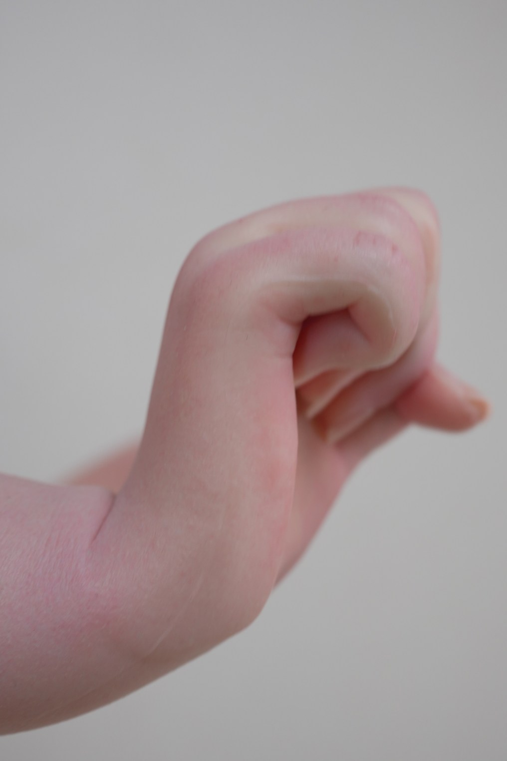 A close-up image of a realistic hand resembling that of a doll, showcasing intricate details in the skin texture and fingers.